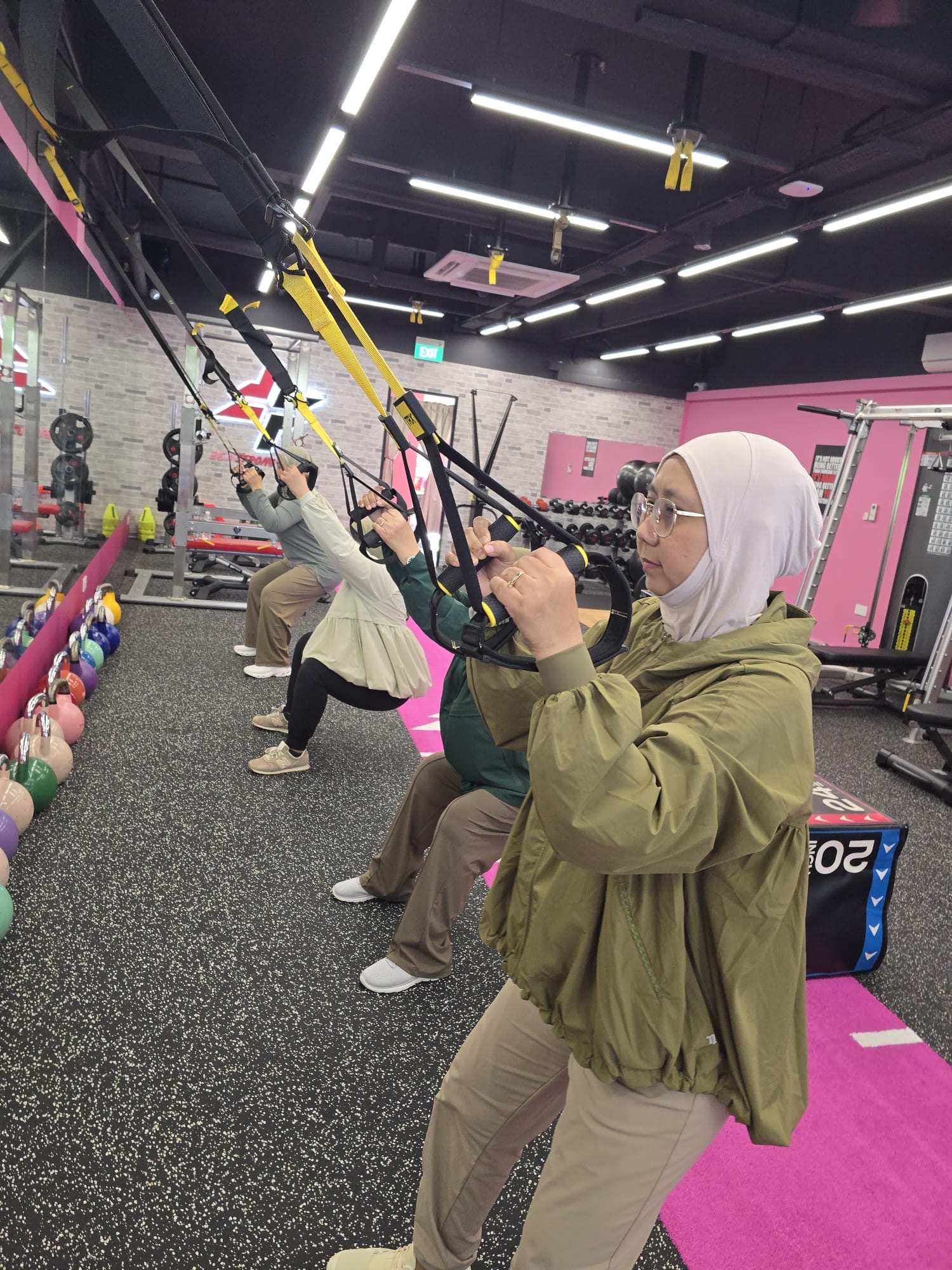 Women training on TRX suspension straps at FitFab.sg
