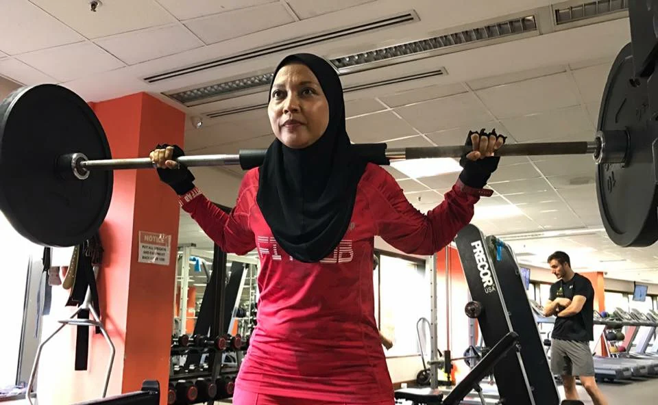 Haslinda Ali pressing a loaded barbell at the gym